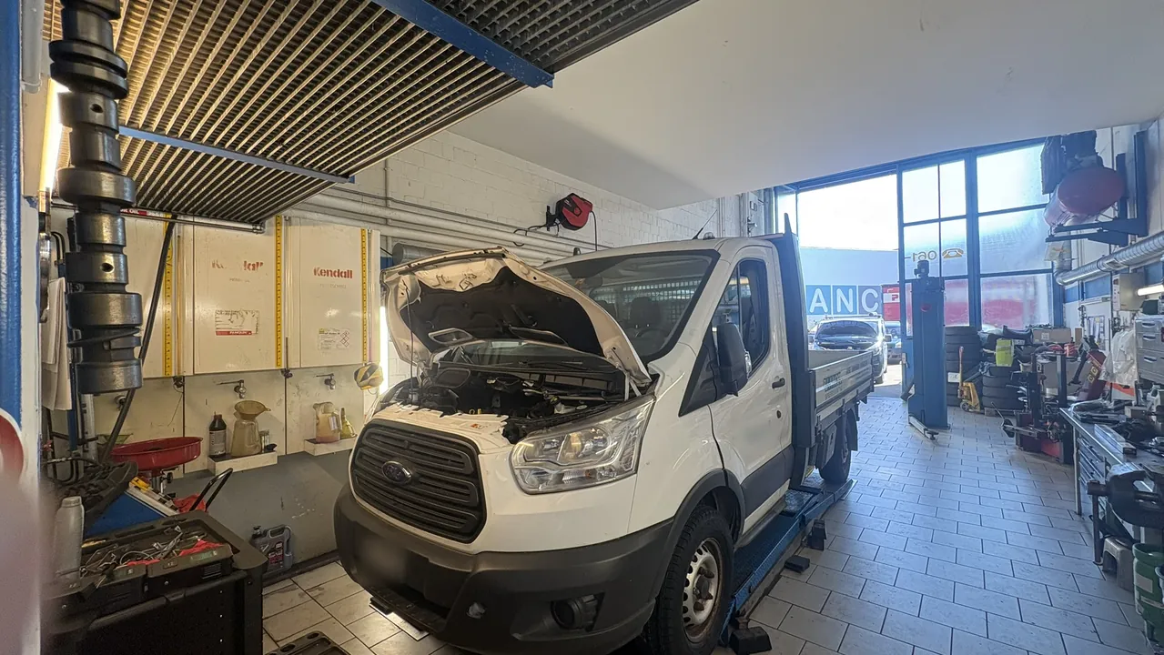 Blick in die Werkstatt der Rotterdam Garage: ein Lieferwagen mit geöffneter Motorhaube auf der Hebebühne.